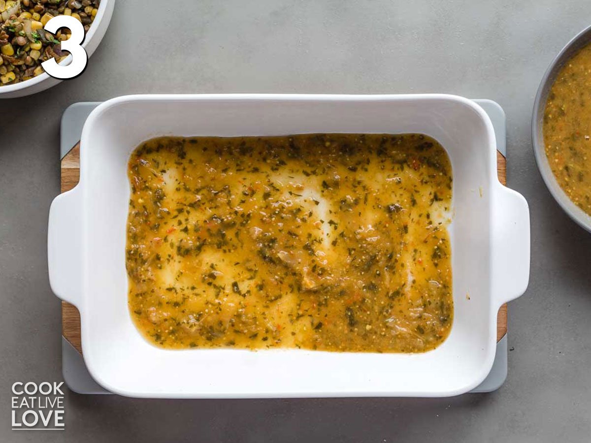 Casserole dish with green enchilada sauce on the bottom