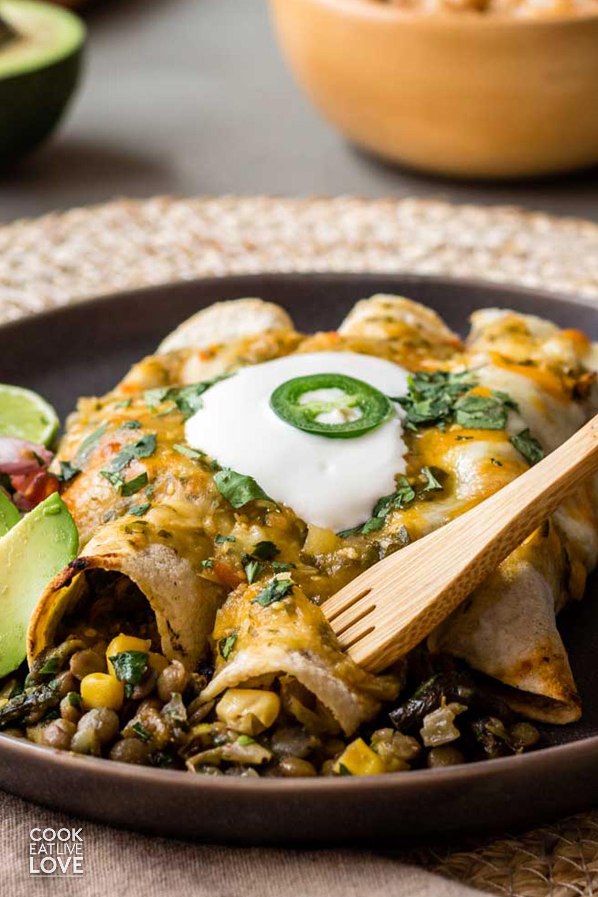 Green enchiladas on a plate with a fork digging in.