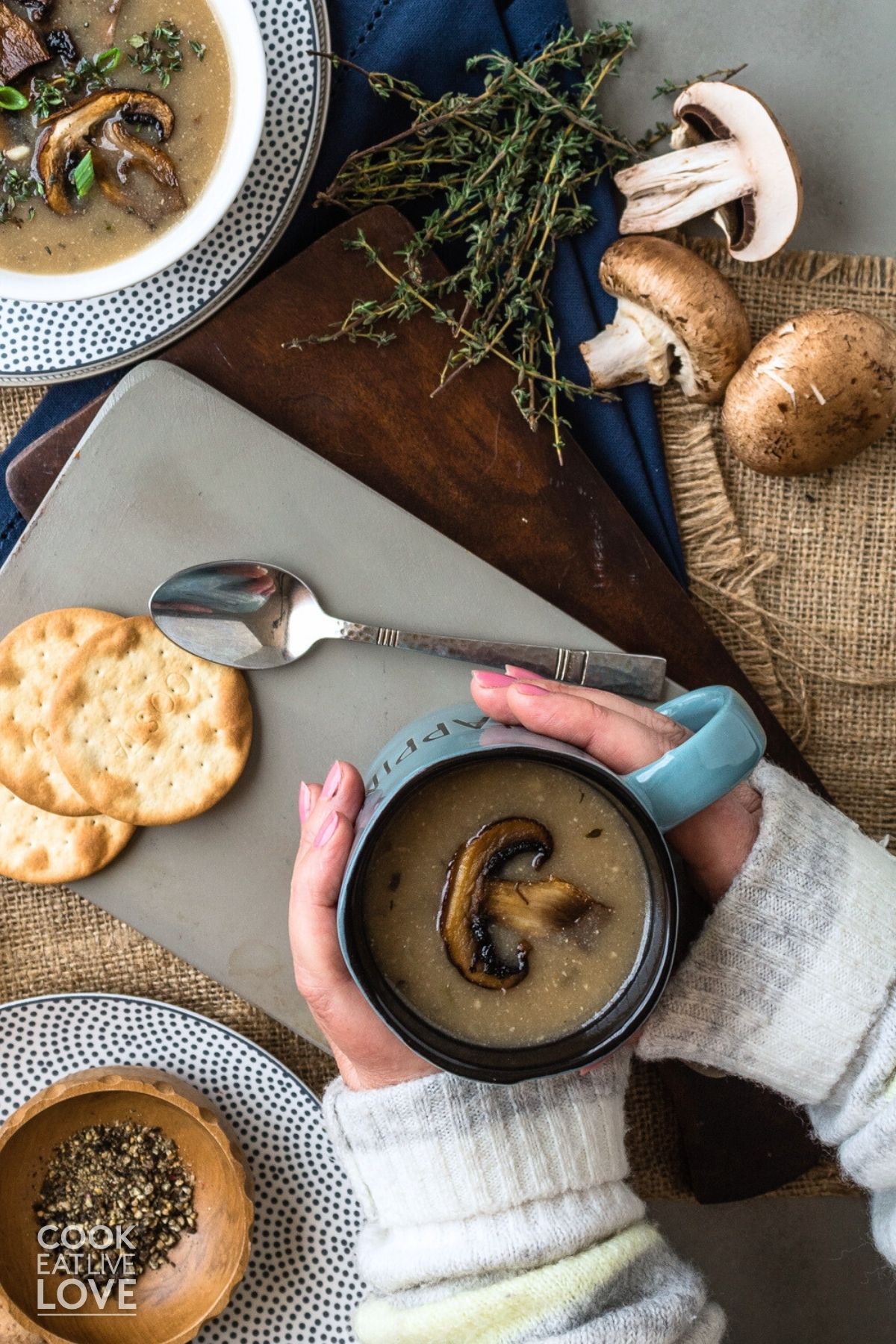 Hands grabbing a mug of vegan mushroom soup without cream on the table. 