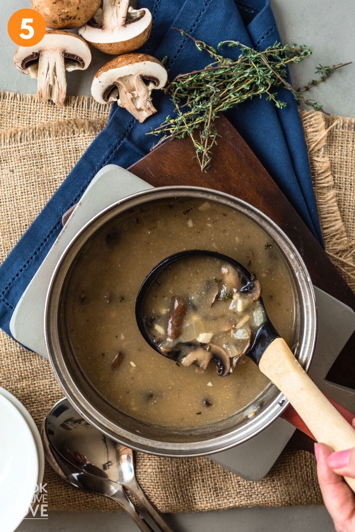A pot of vegan mushroom soup with a ladle lifting some up.