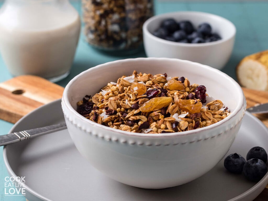 Bowl of nut-free granola on the table with milk and berries.