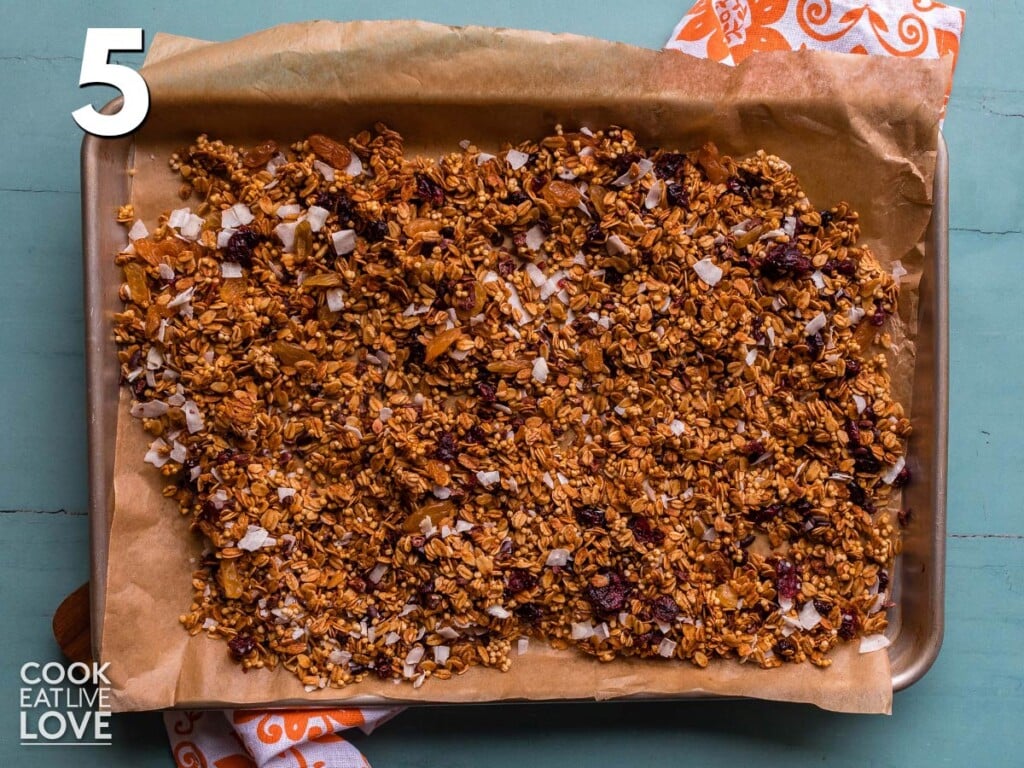 Mixed nut free granola is returned to baking tray to cool down.