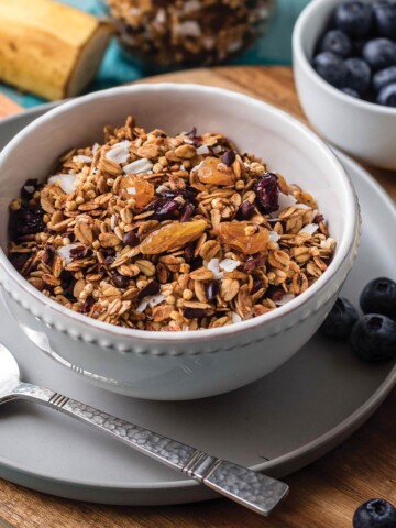 Bowl of nut free granola on a plate with a spoon.