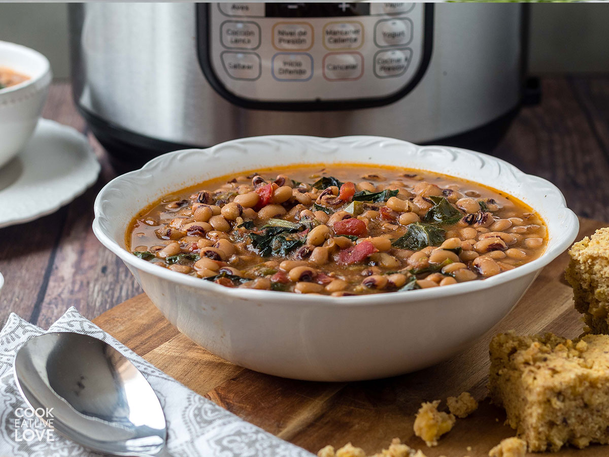 A bowl of vegetarian black eyed peas in front of an instant pot.