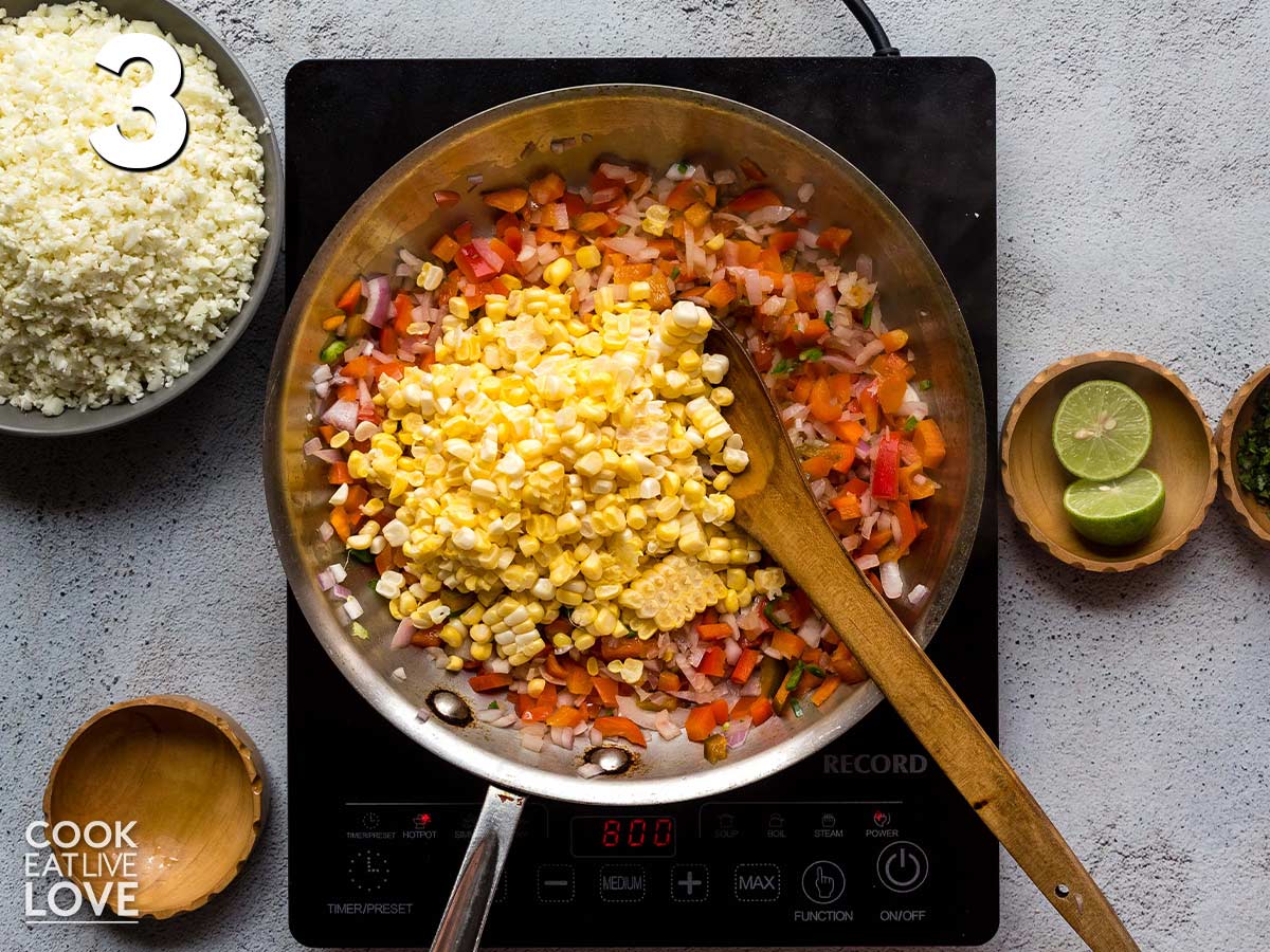 Adding the corn to the pan making cauliflower rice for burrito bowls.