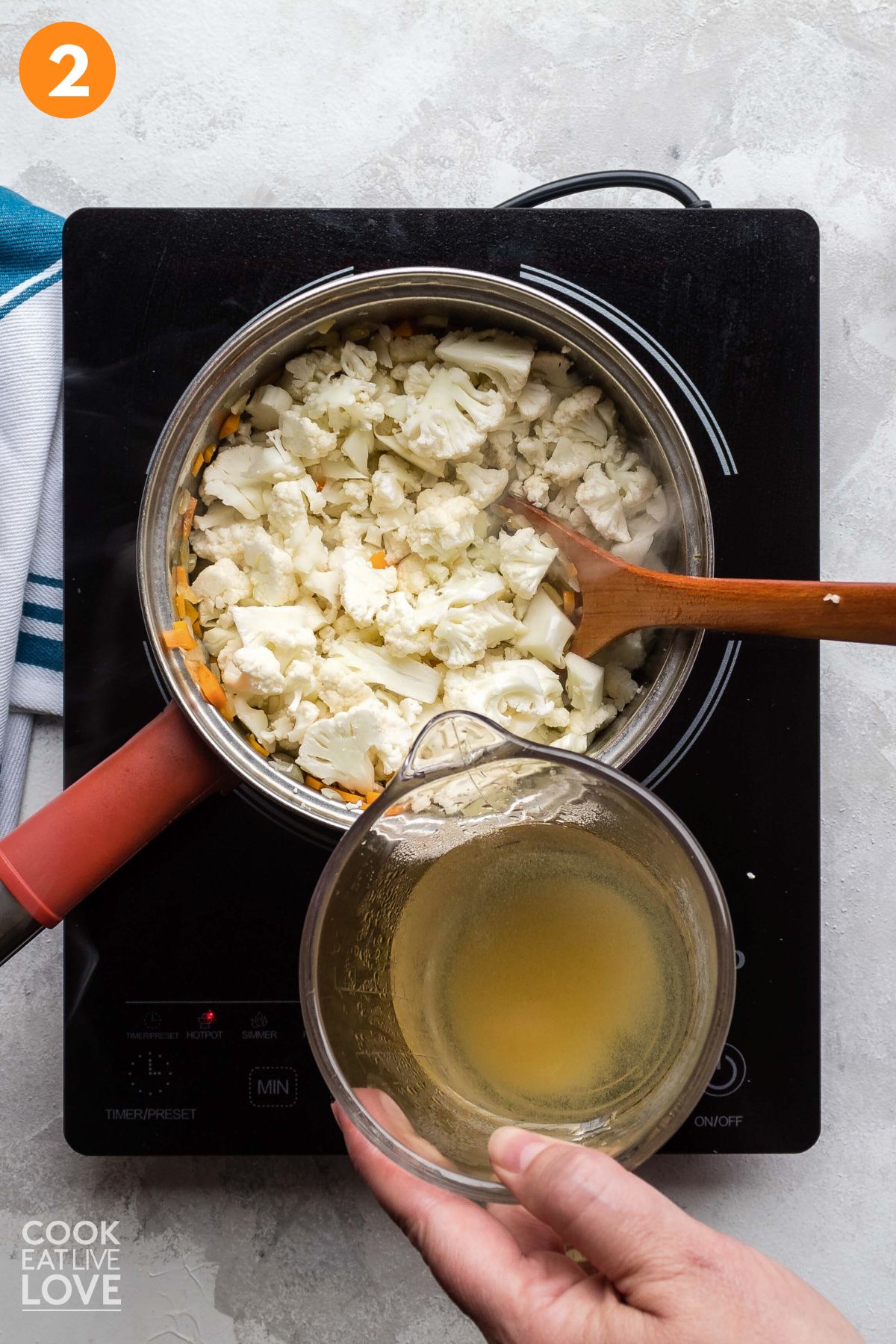 Cauliflower added to the pot and a pitcher of broth held to the side.