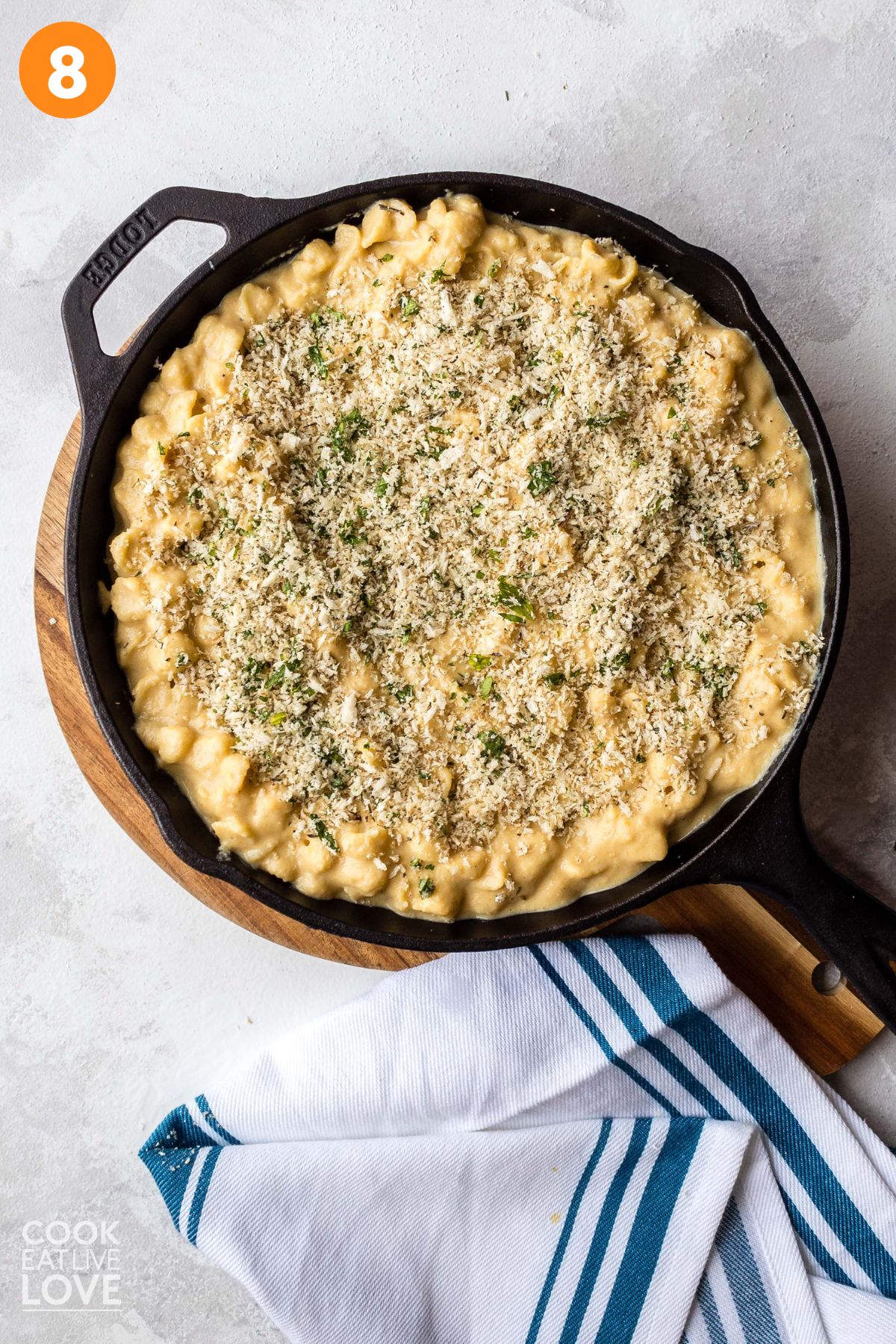 Breadcrumbs sprinkled on top of the vegan mac and cheese in a skillet.