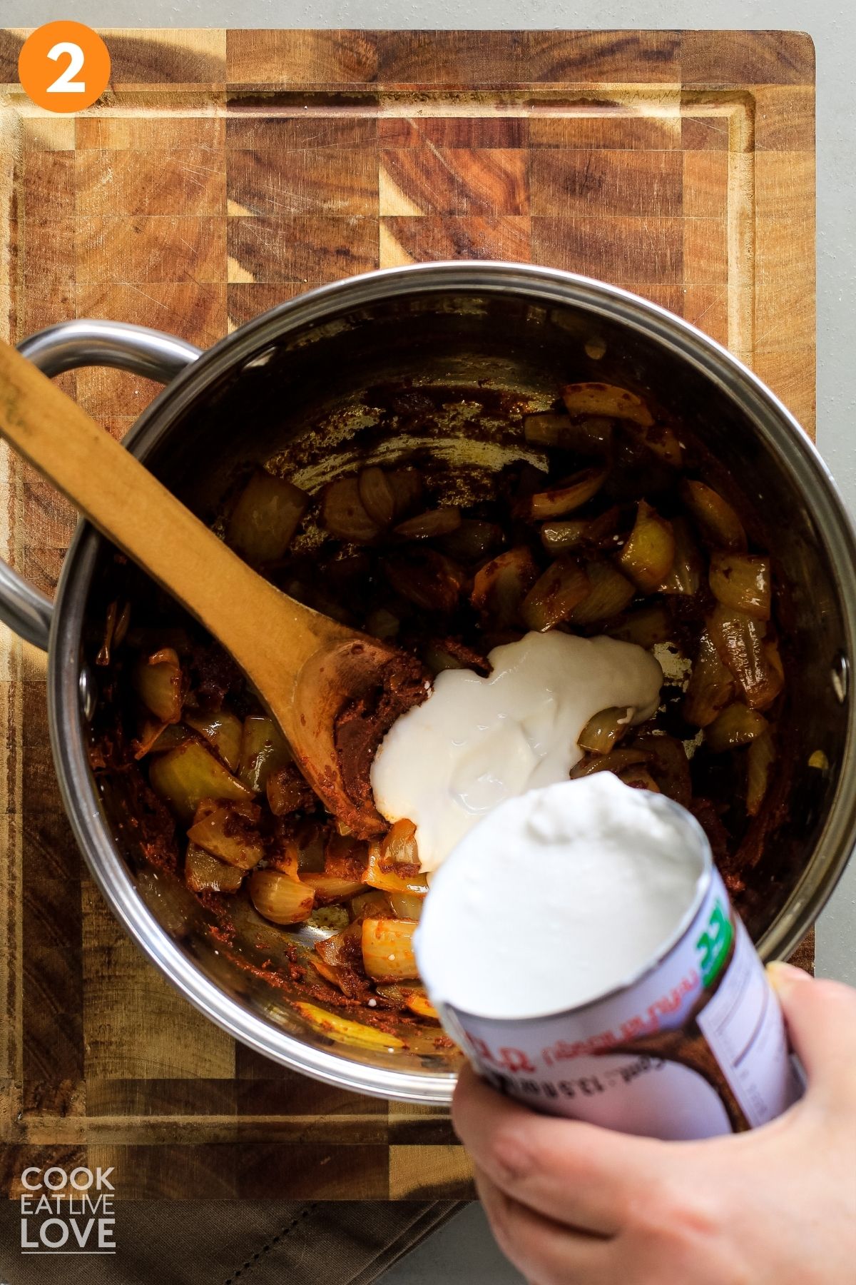Adding coconut milk to the pot to cook. 