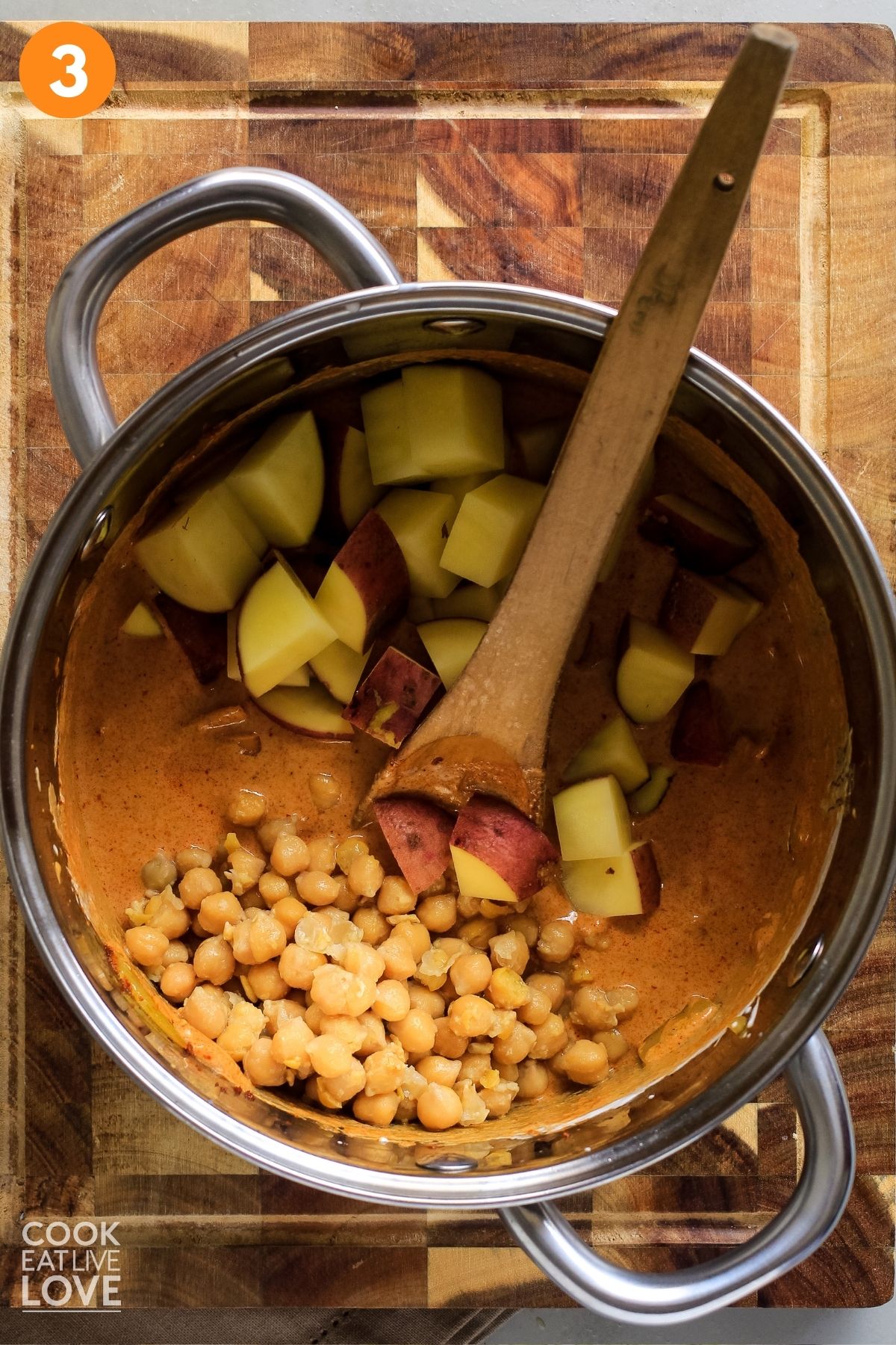 Chickpeas and potatoes added to the pot of massaman curry sauce. 