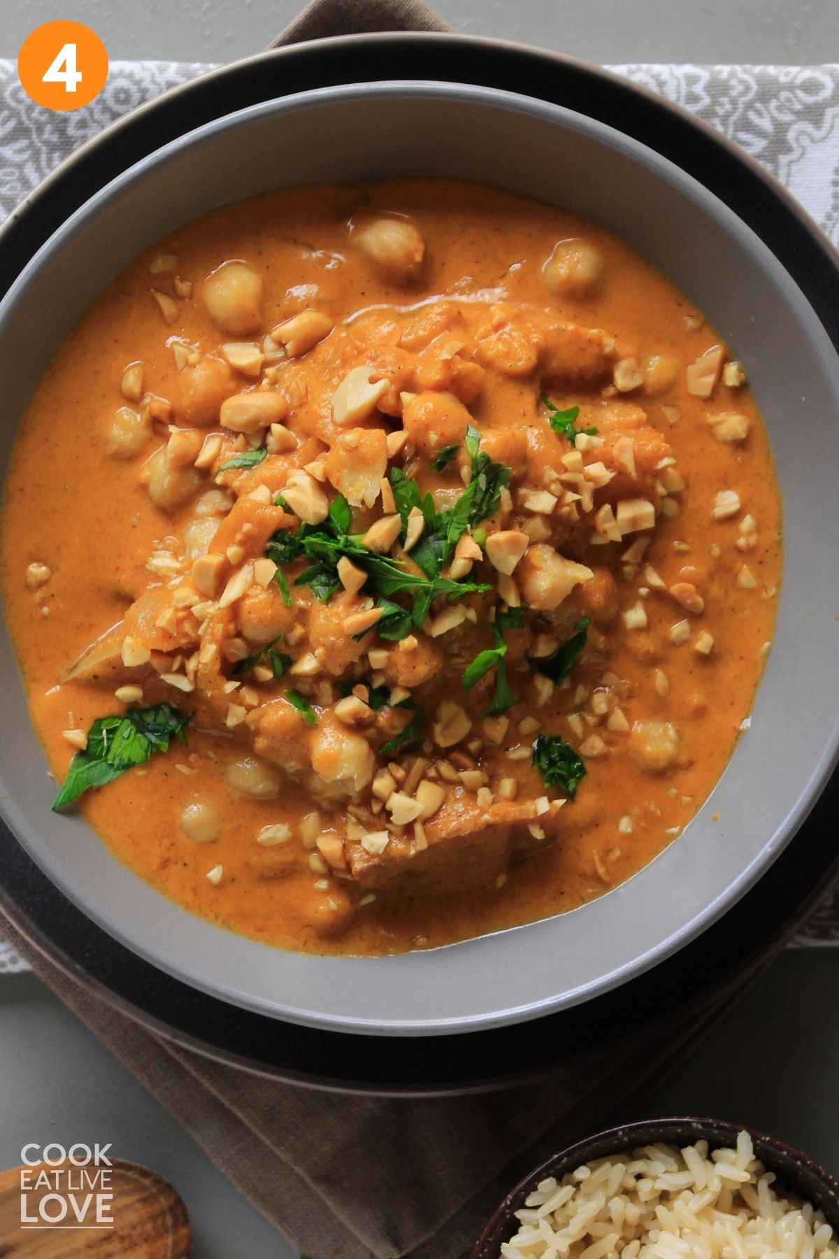 A bowl of vegan massaman curry garnished with herbs and chopped peanuts. 