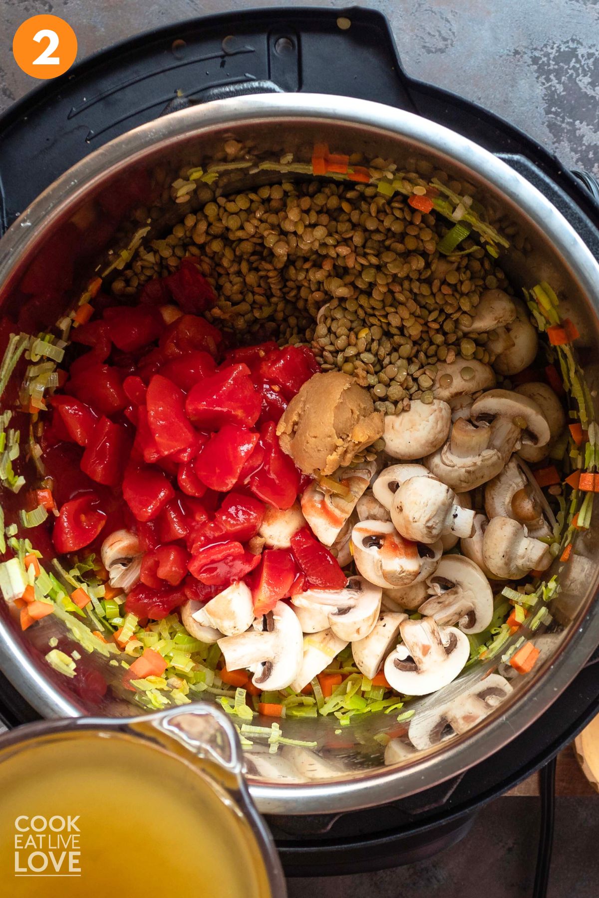 Adding the mushrooms, tomatoes, and broth to the pot.