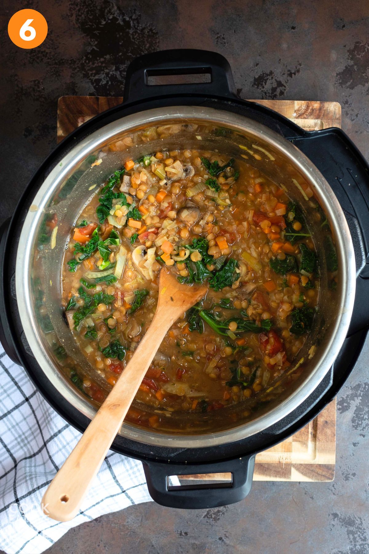 Mushroom lentil stew in the instant pot with a wooden spoon in the pot.