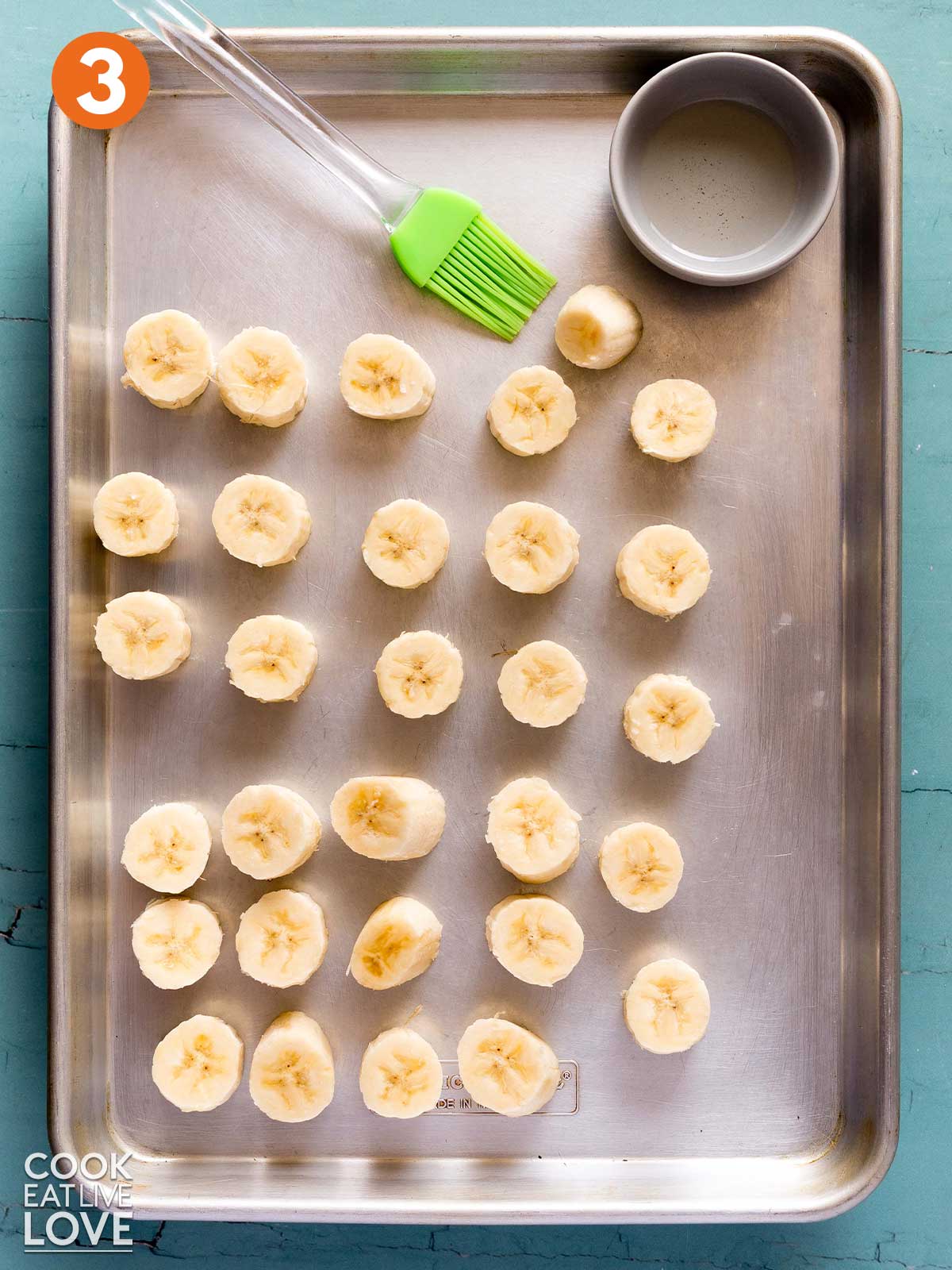 Cut bananas laid out on a baking tray with coconut oil and pastry brush.