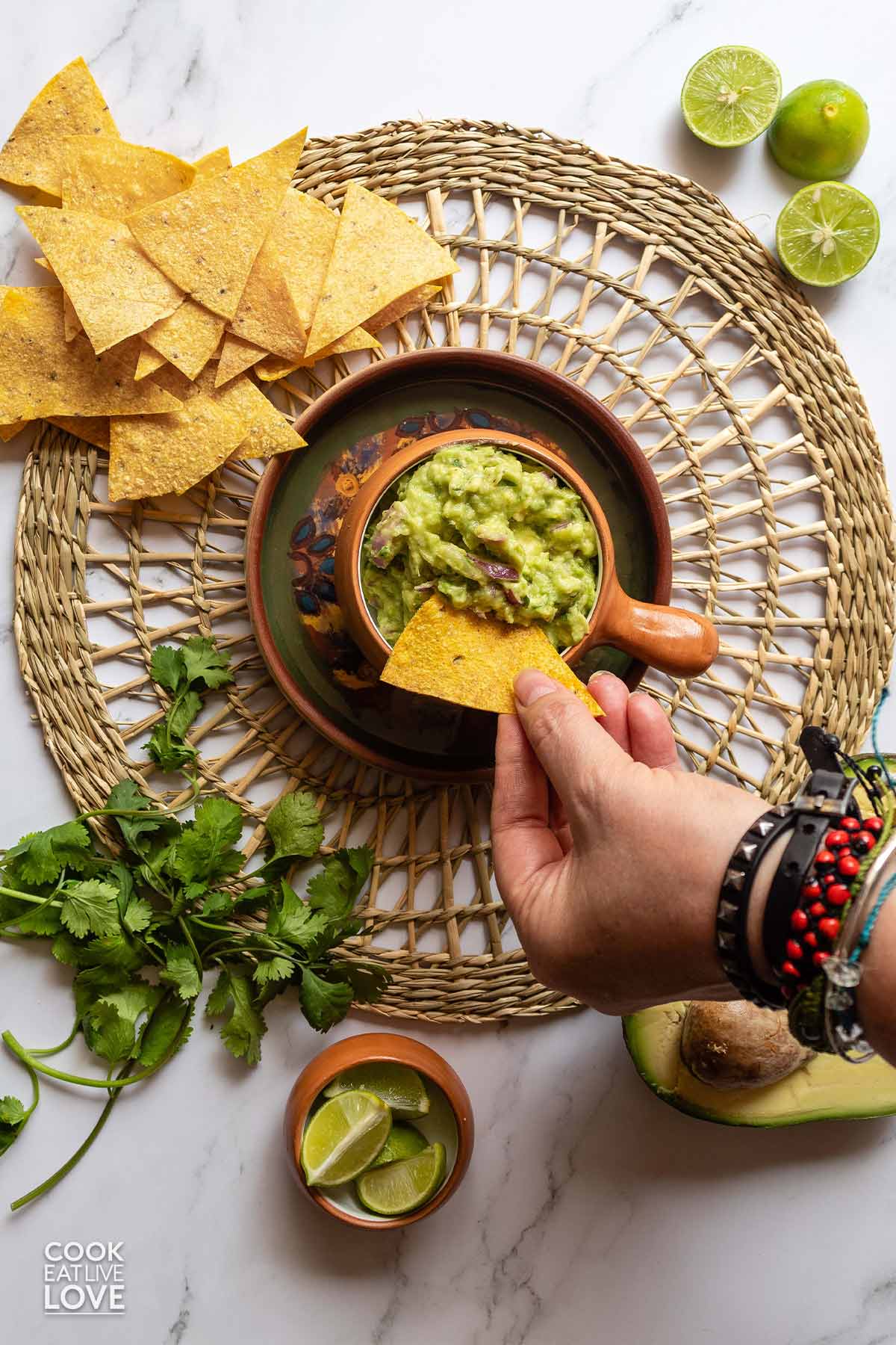 Hand dipping a chip into a bowl of guacamole.