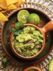 4-ingredient guacamole in a bowl with limes and tortilla chips.