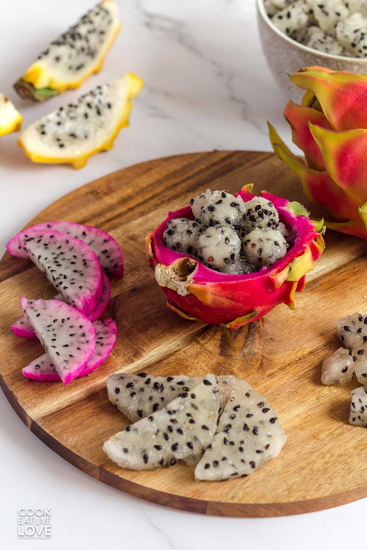 Balls scooped and served in the peel of dragon fruit with slices and cubes around it.