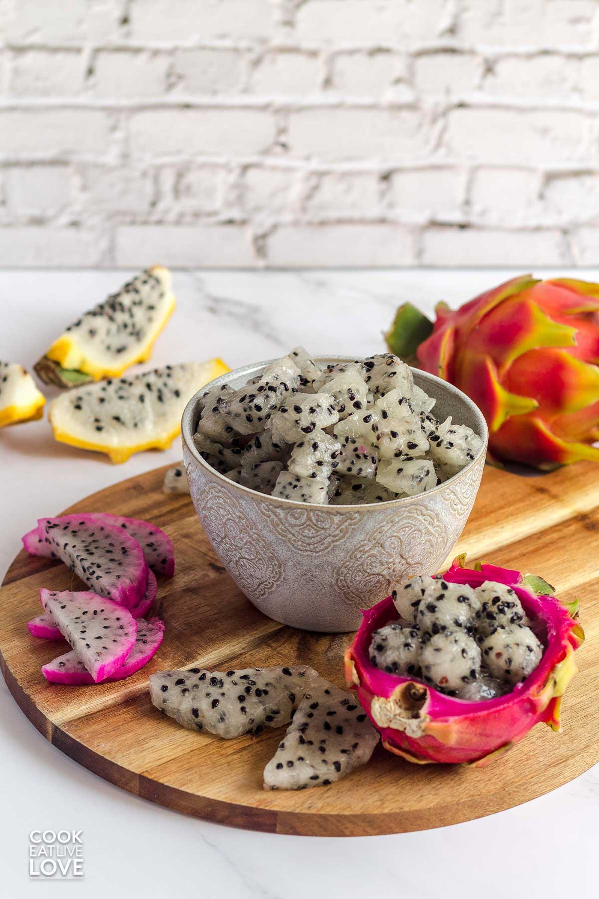 Dragon fruit cut in different shapes, slices, cubes and balls in a bowl and on the table.