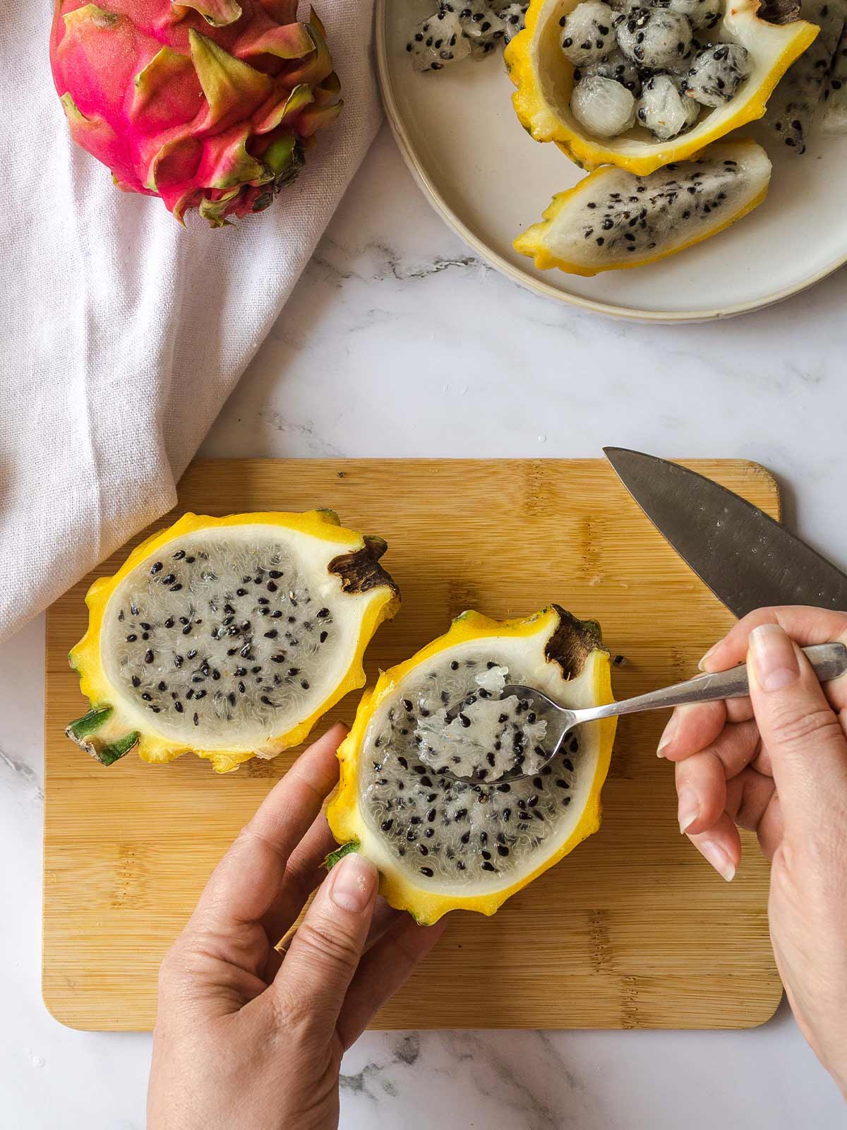 Eating a dragon fruit with a spoon from the cut half of fruit.
