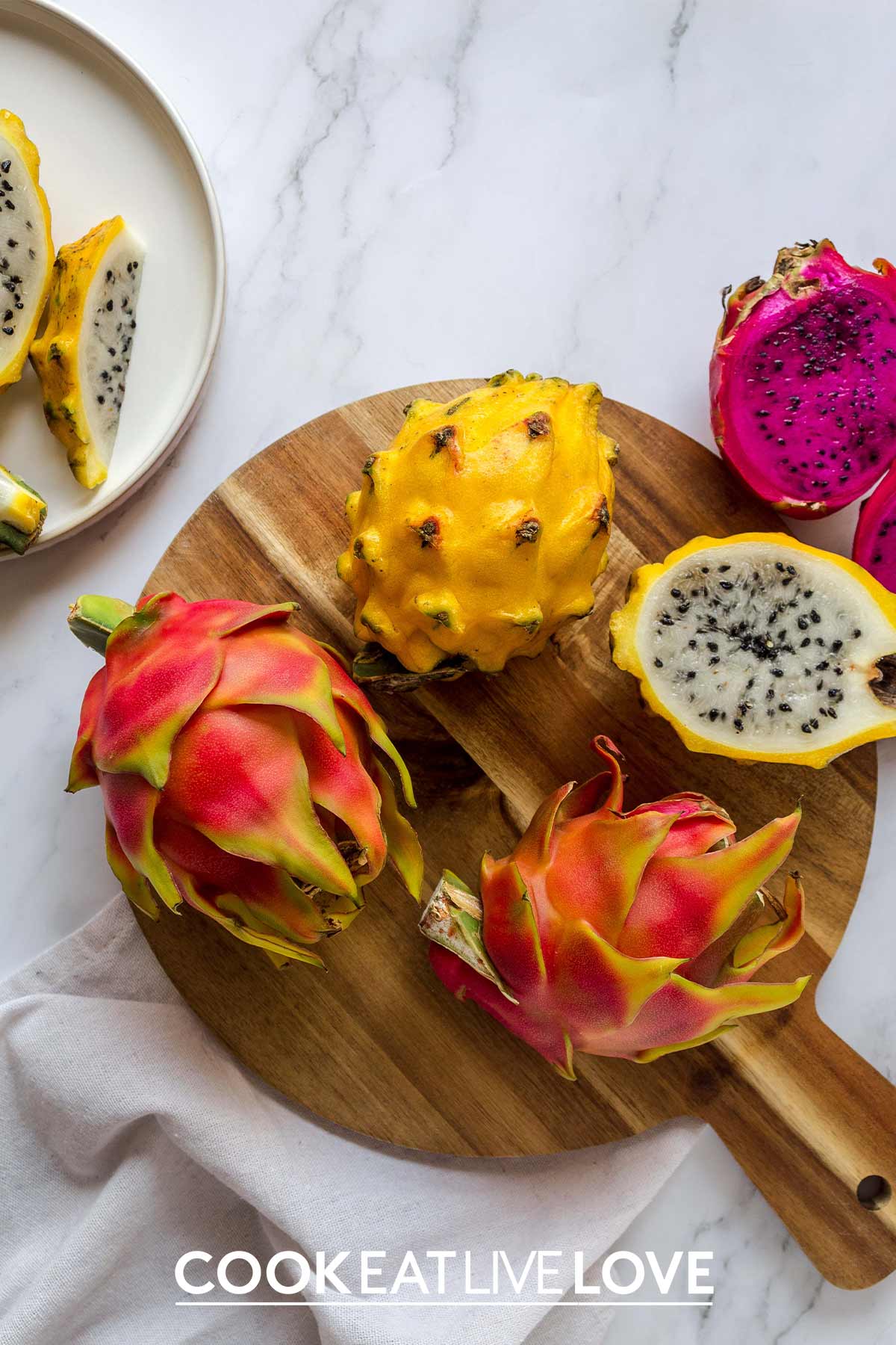 Red-pink dragon fruit and yellow variety on the table whole and cut in half.