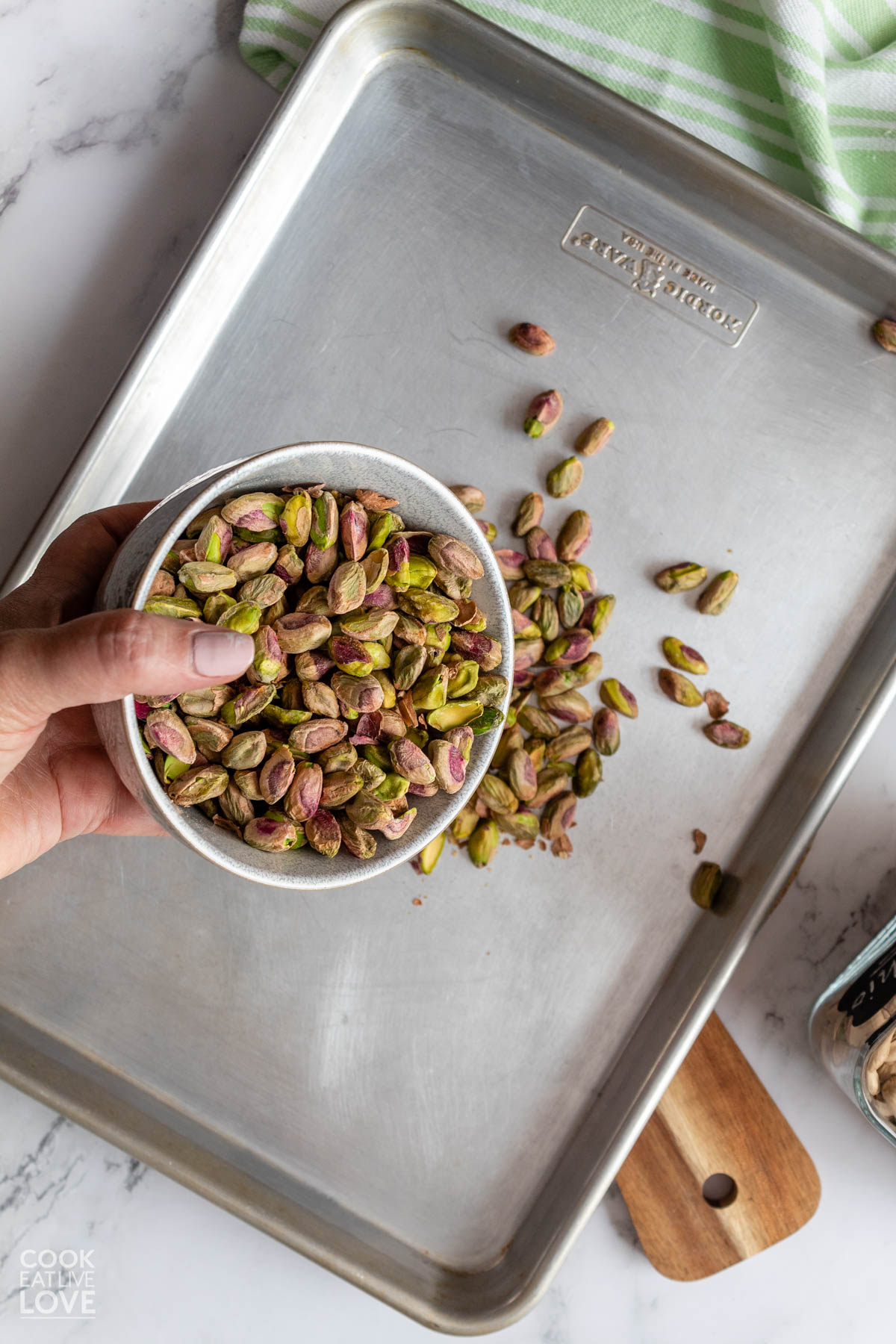 Pouring shelled pistachios to a pan to heat.