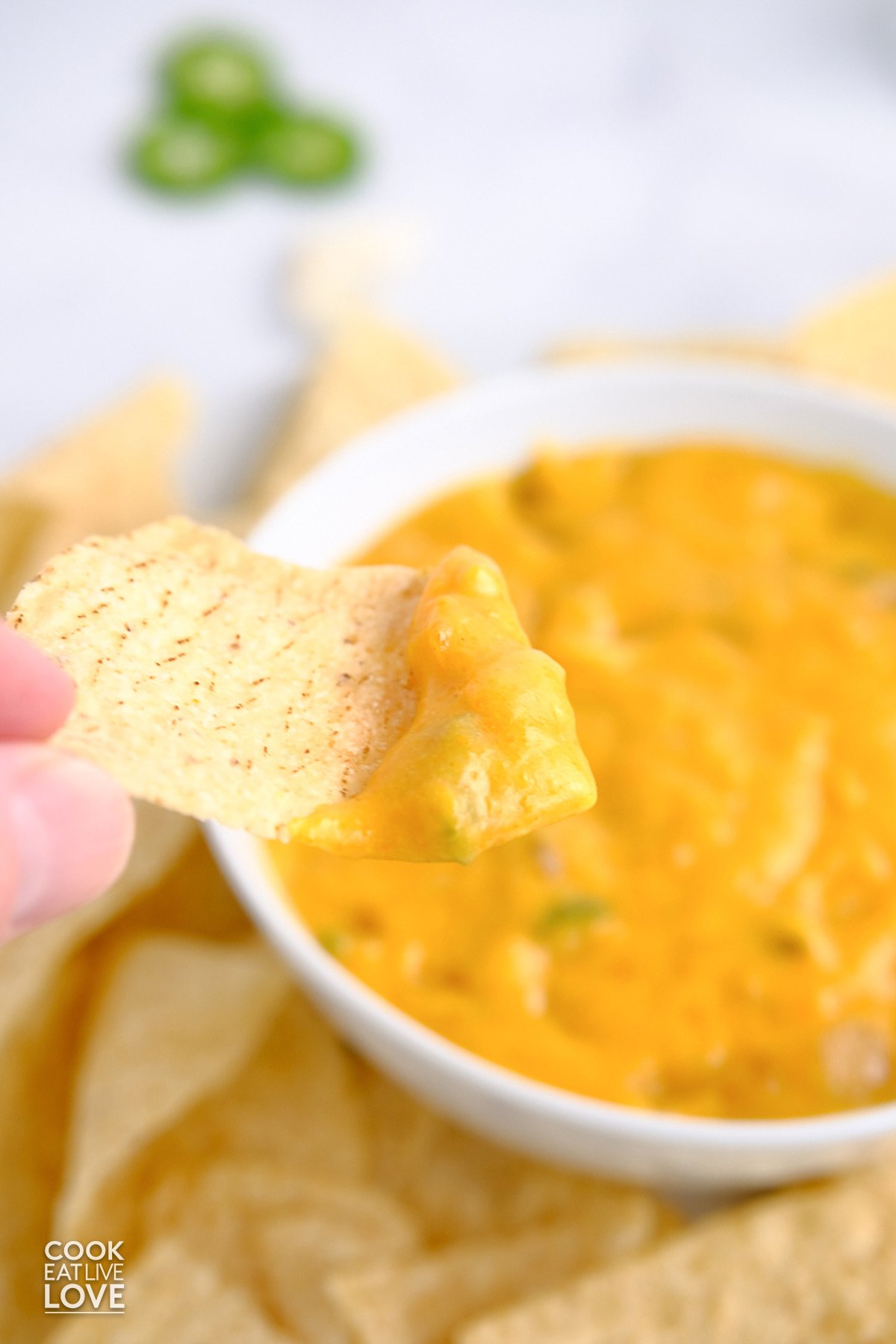 A chip dipping into vegan cheese sauce.