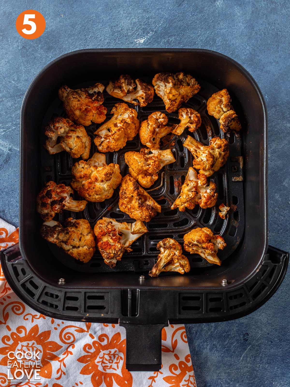 Cooked buffalo cauliflower in the air fryer basket.