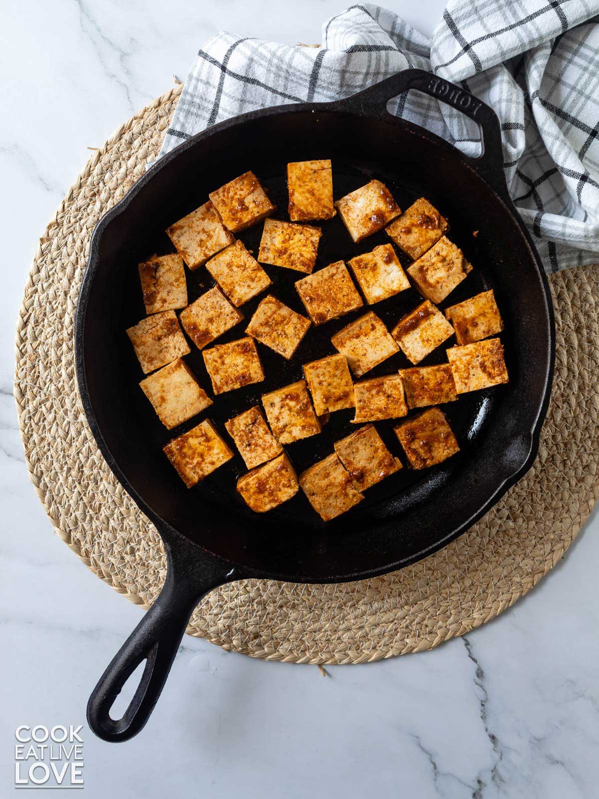 Marinated tofu placed in a cast iron skillet to cook.