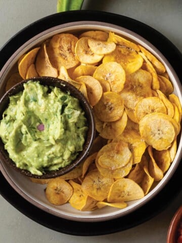 Bowl of air fryer plantain chips on the table with guacamole.