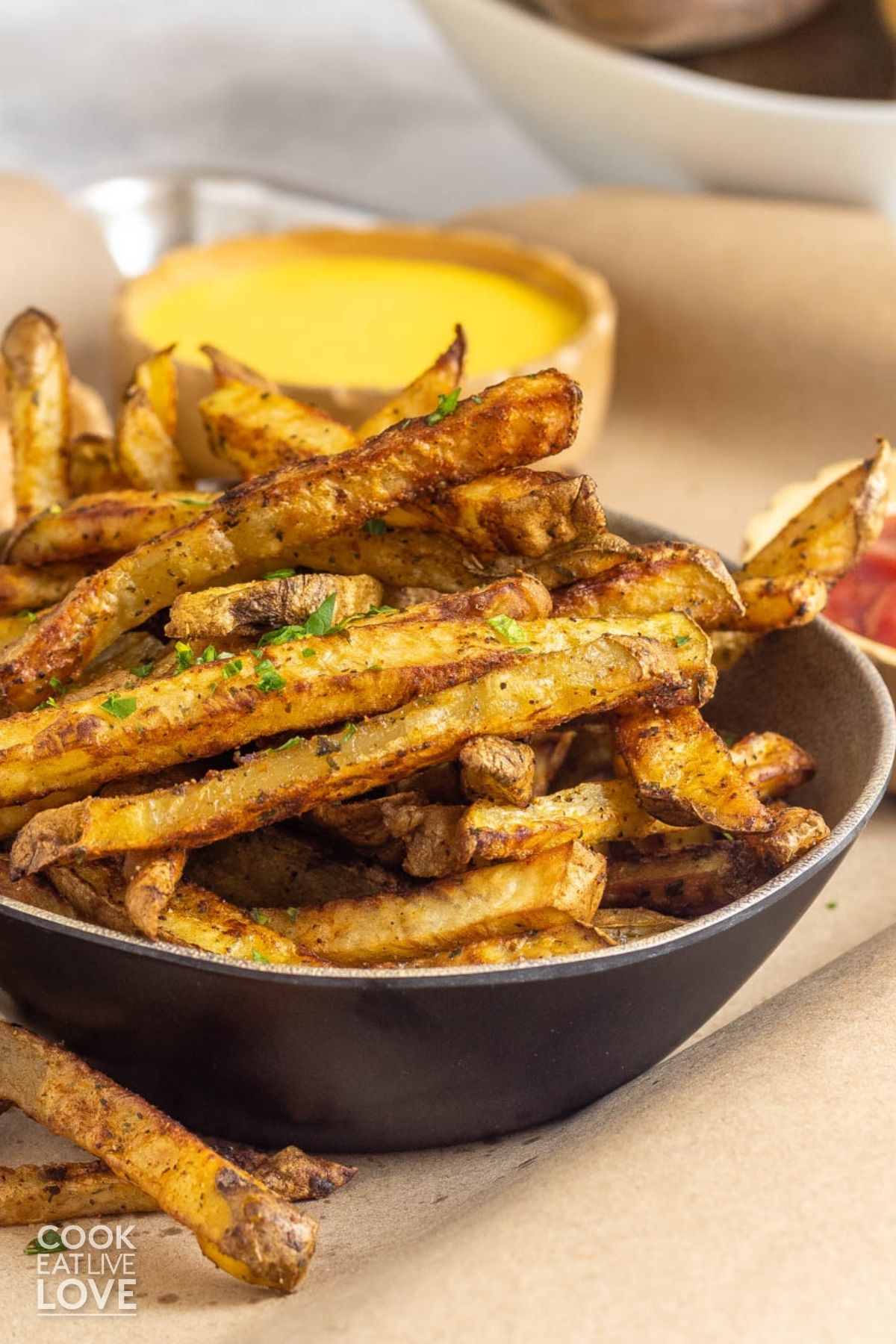 A bowl of oven french fries in a bowl with some sauces. 