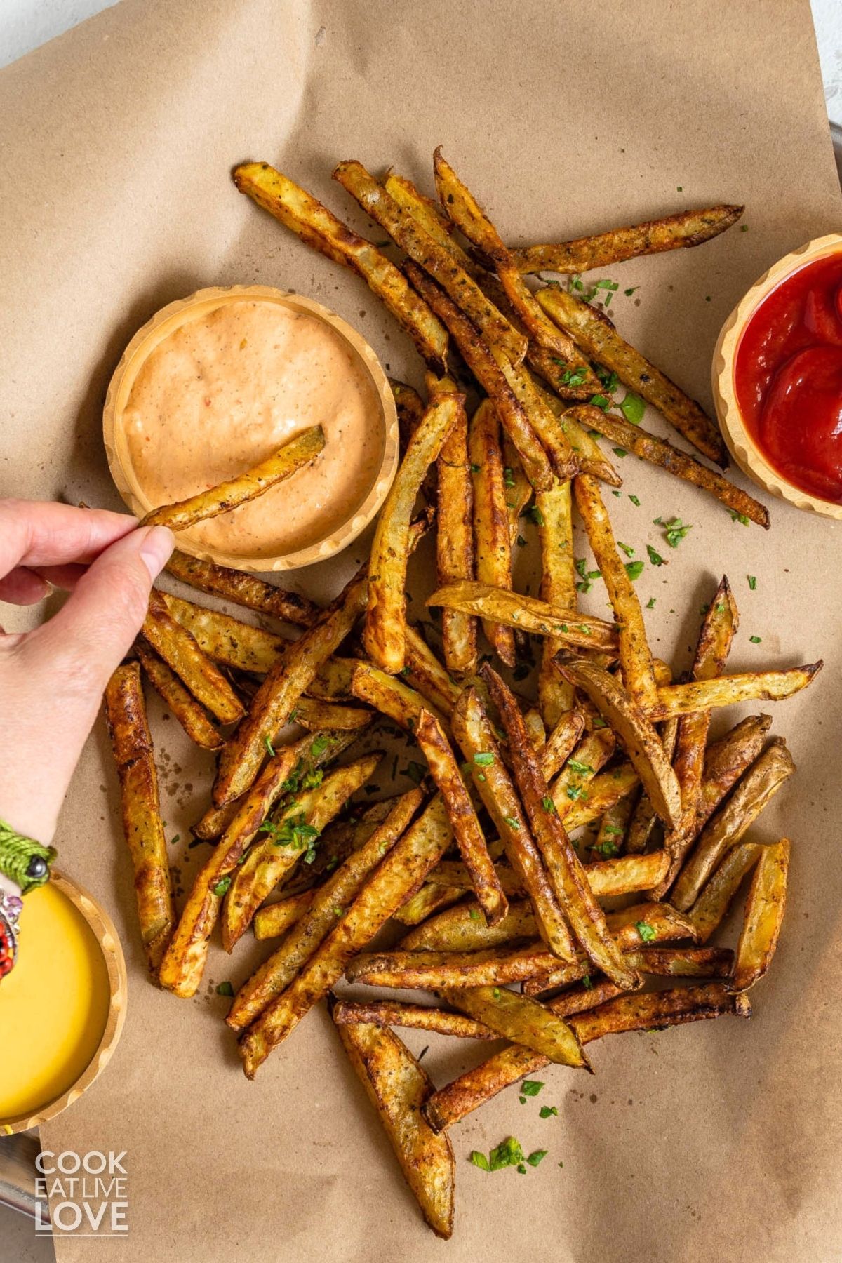 Hand dipping a french fry into sauce.