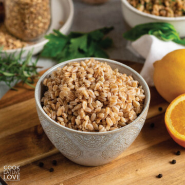 Bowl of farro instant pot on the table with citrus and herbs.