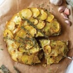 Potato galette on a piece of parchment paper with slice cut and pulled out slightly.