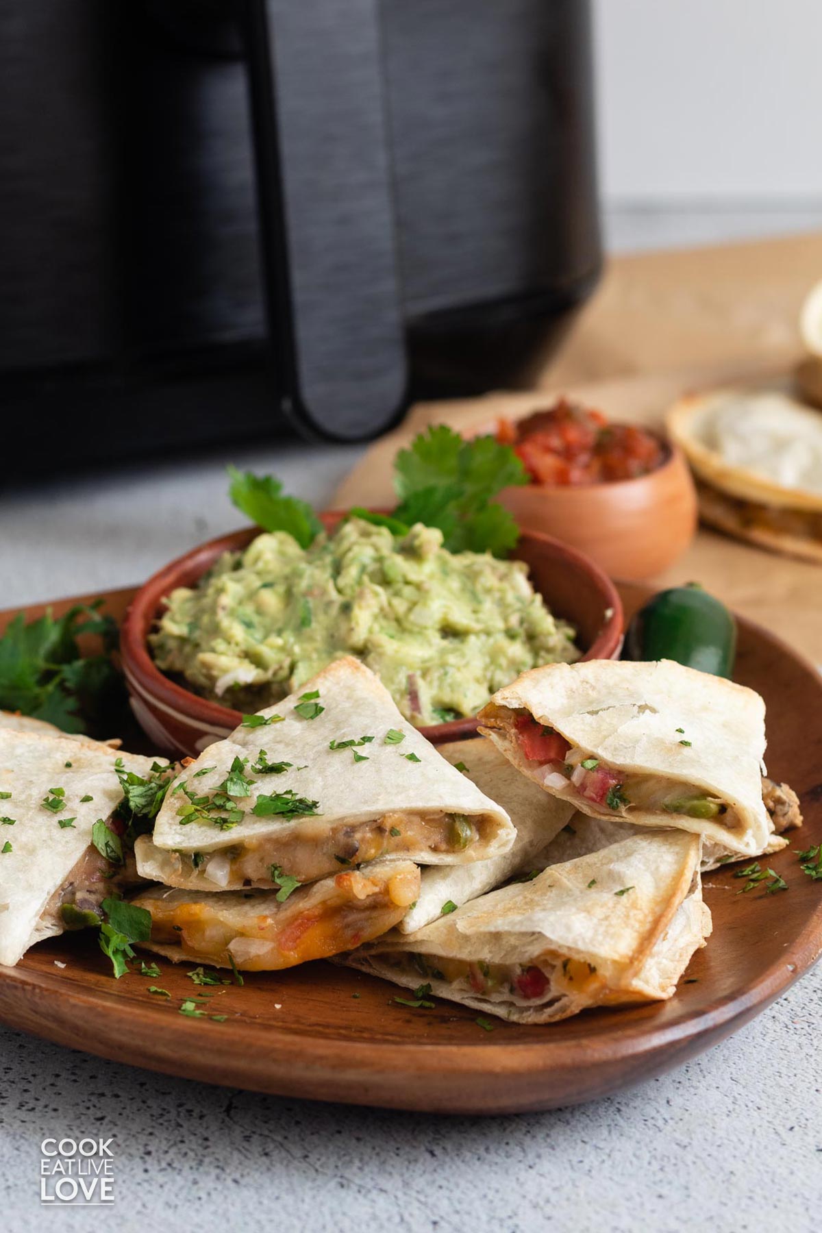 Air fryer quesadillas on the table in front of an air fryer.
