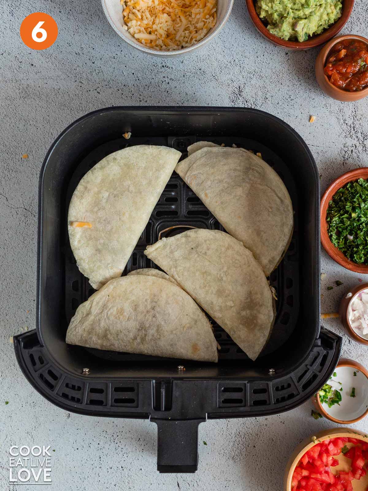Air fryer quesadillas placed inside the air fryer basket to cook.