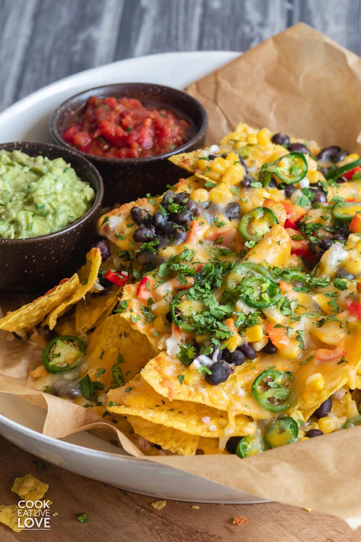 Platter of vegetarian nachos on the table with guacamole and salsa.