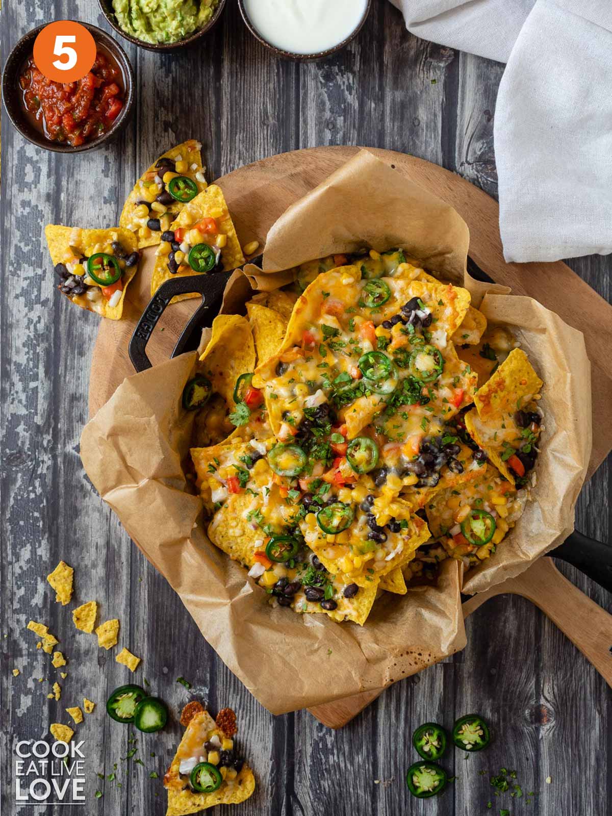 Tortilla chips layered with veggies and beans for vegetarian nachos.
