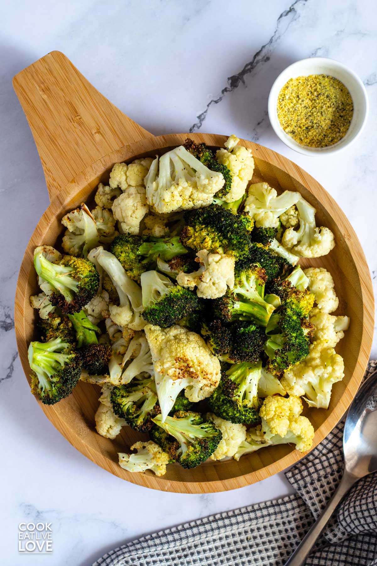Air fryer broccoli and cauliflower in wooden serving bowl on the table.