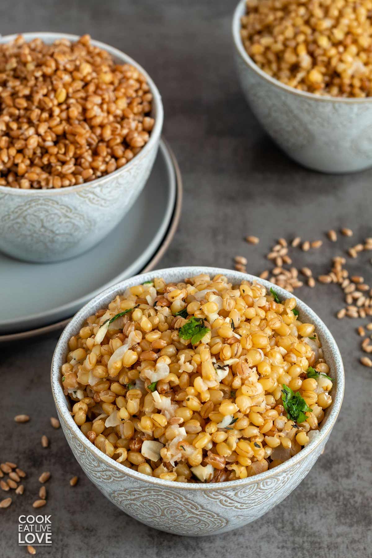 Three different kinds of cooked wheat berries in bowls on the table.