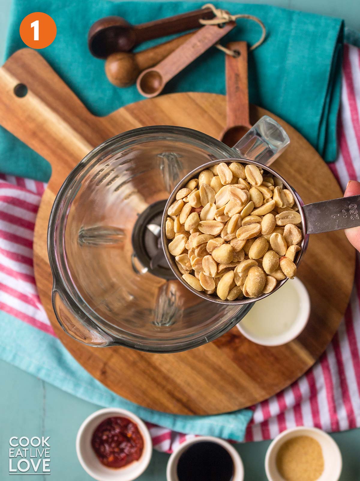 A measuring cup of peanuts up over a blender.