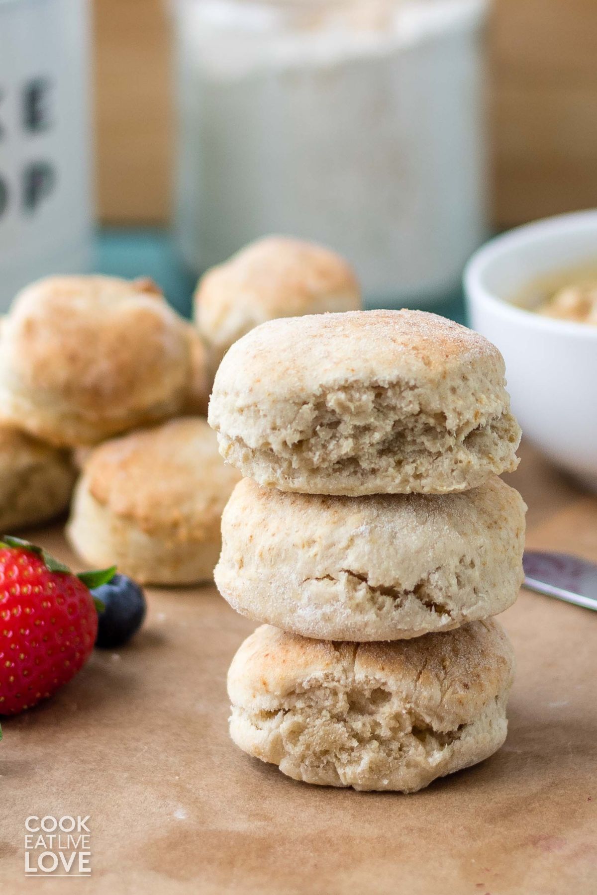 Three air fryer biscuits stacked on the cutting board with more in the back.