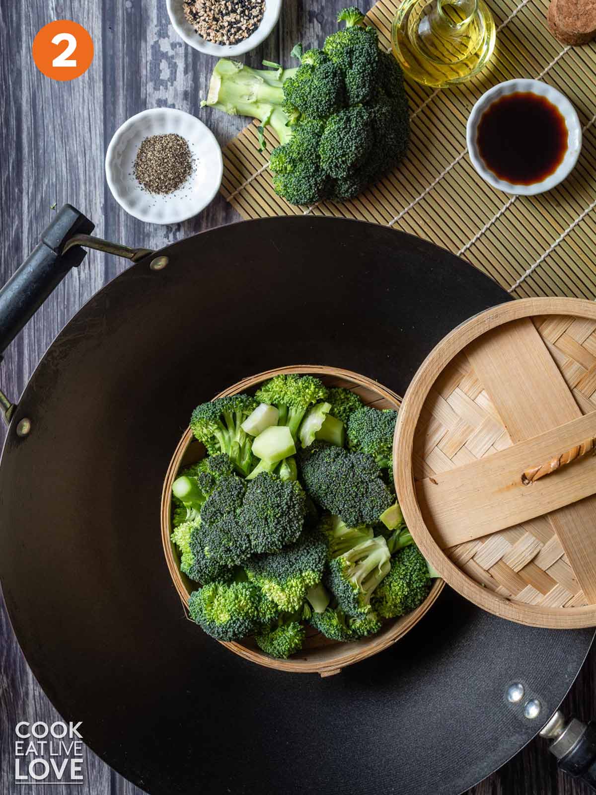 Broccoli in a steamer basket set inside a wok.