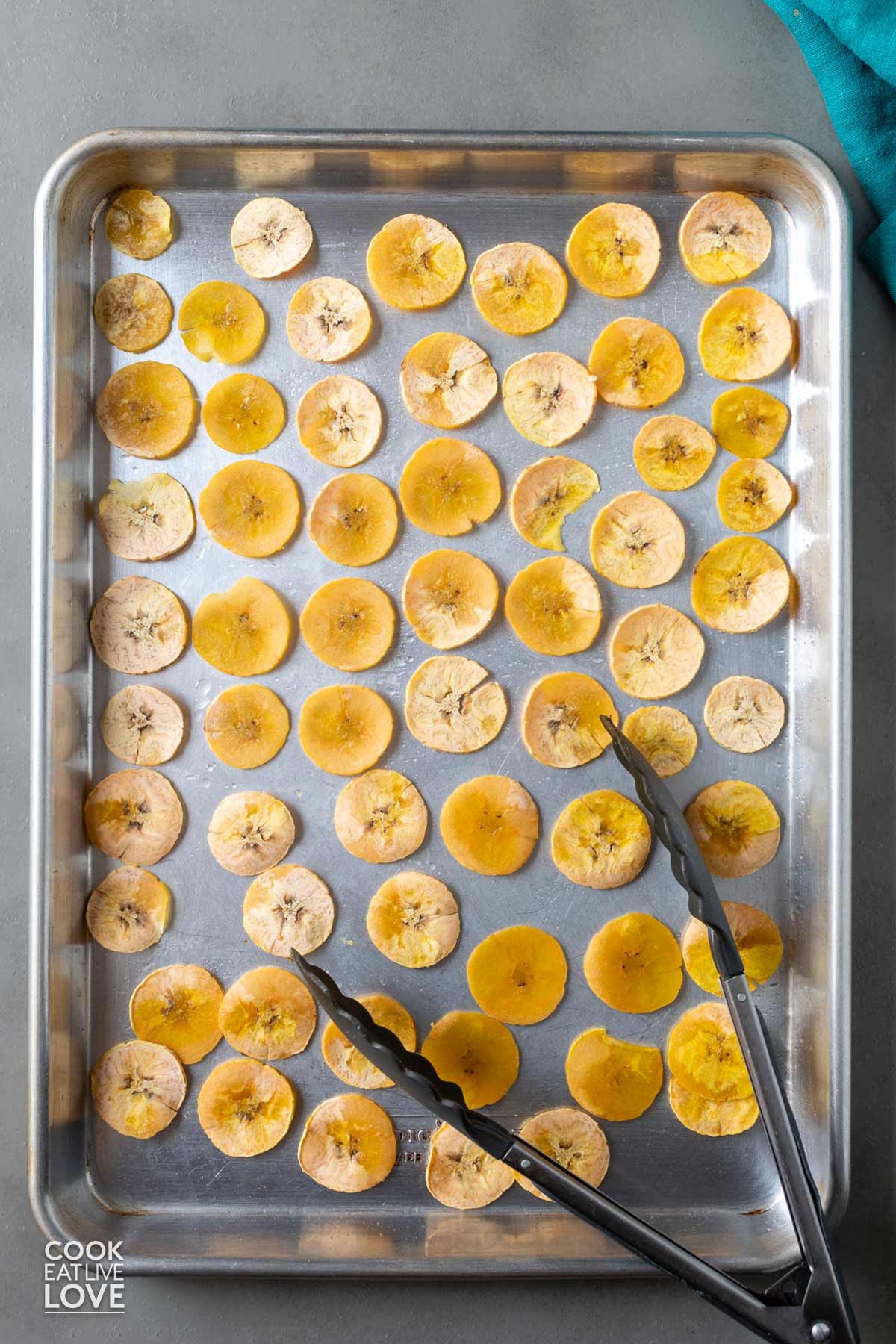 Baking tray of plantain slices after cooking and flipping.