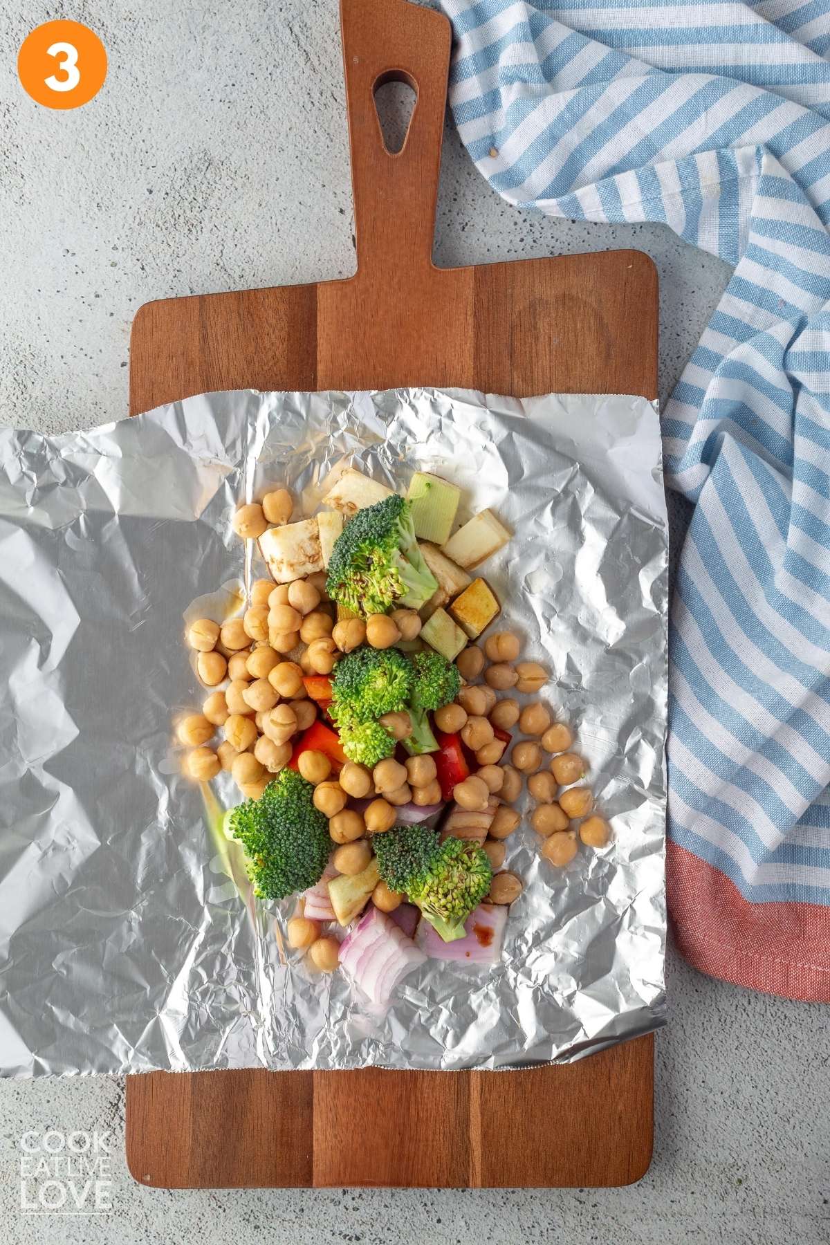 Chickpeas added to veggies on top of sheet of foil.