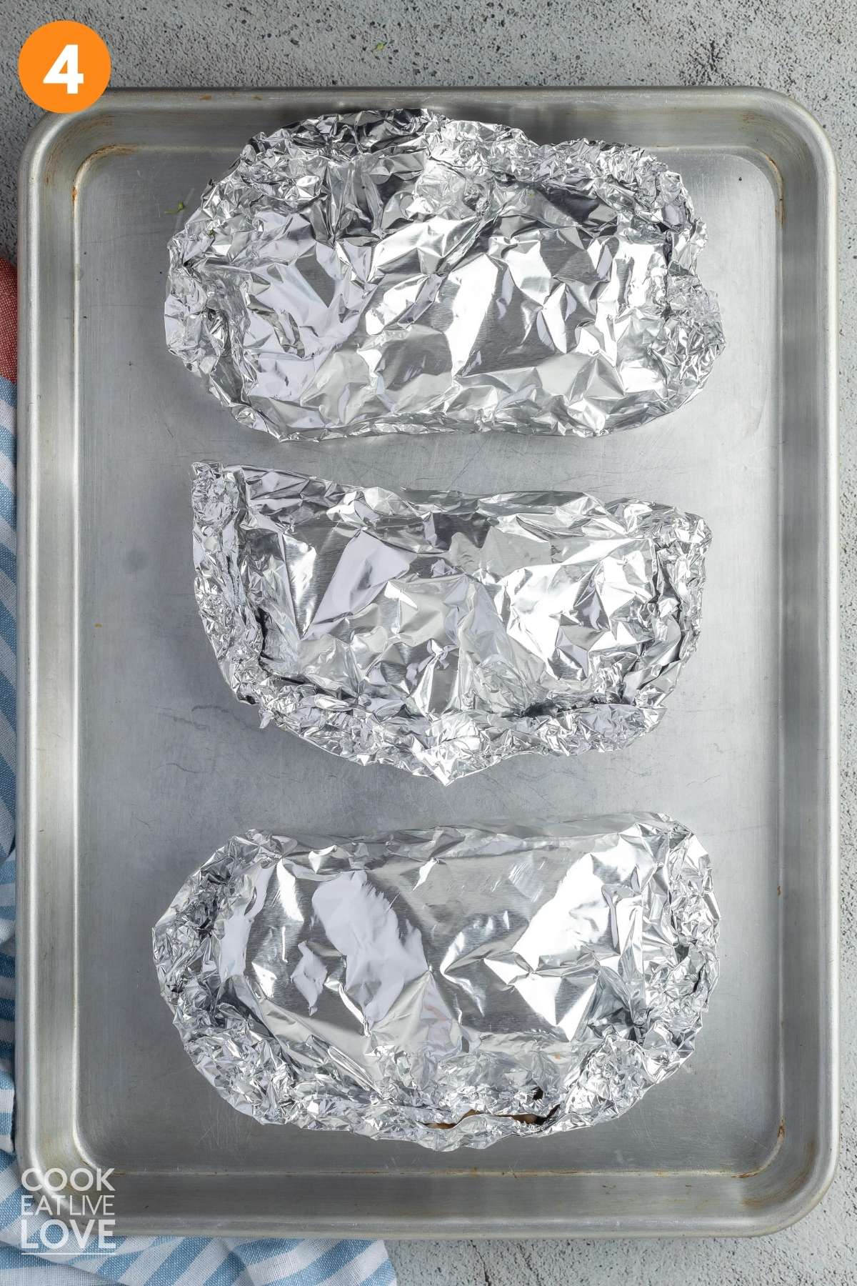 Three vegetable foil packs on a baking pan.