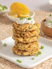 A plate of baked zucchini fritters on a wicker mat on the table.
