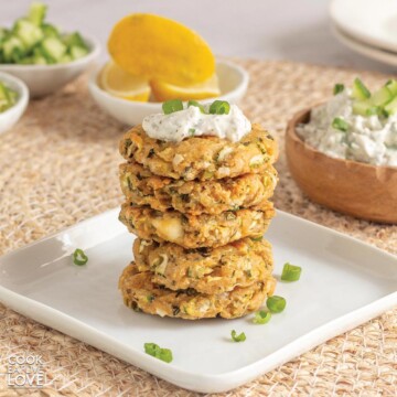 A plate of baked zucchini fritters on a wicker mat on the table.