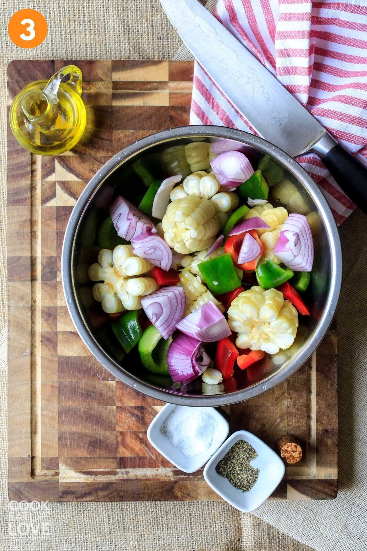 Chopped veggies in a bowl with a bottle of olive oil in the corner.