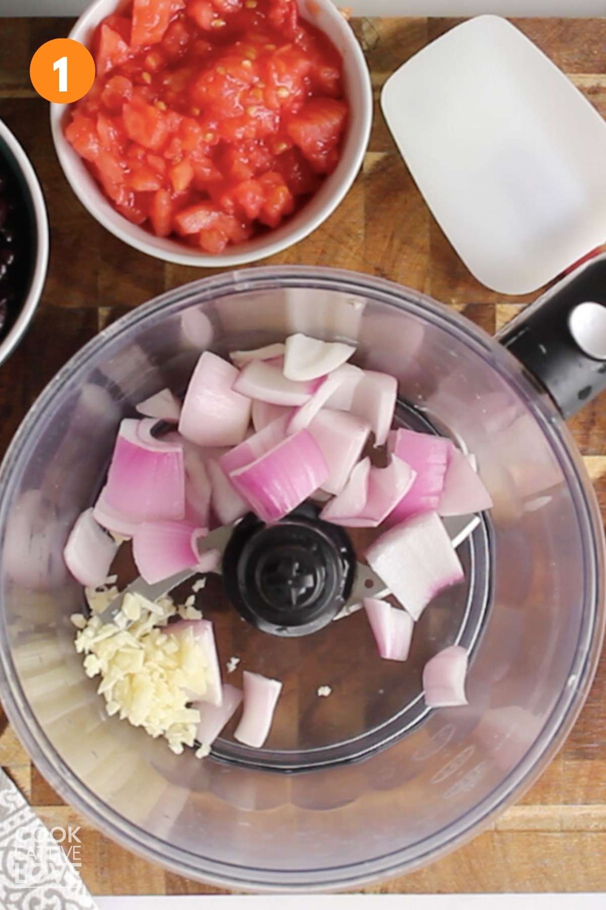 Food processor with red onions and garlic to start making black bean quinoa burgers.