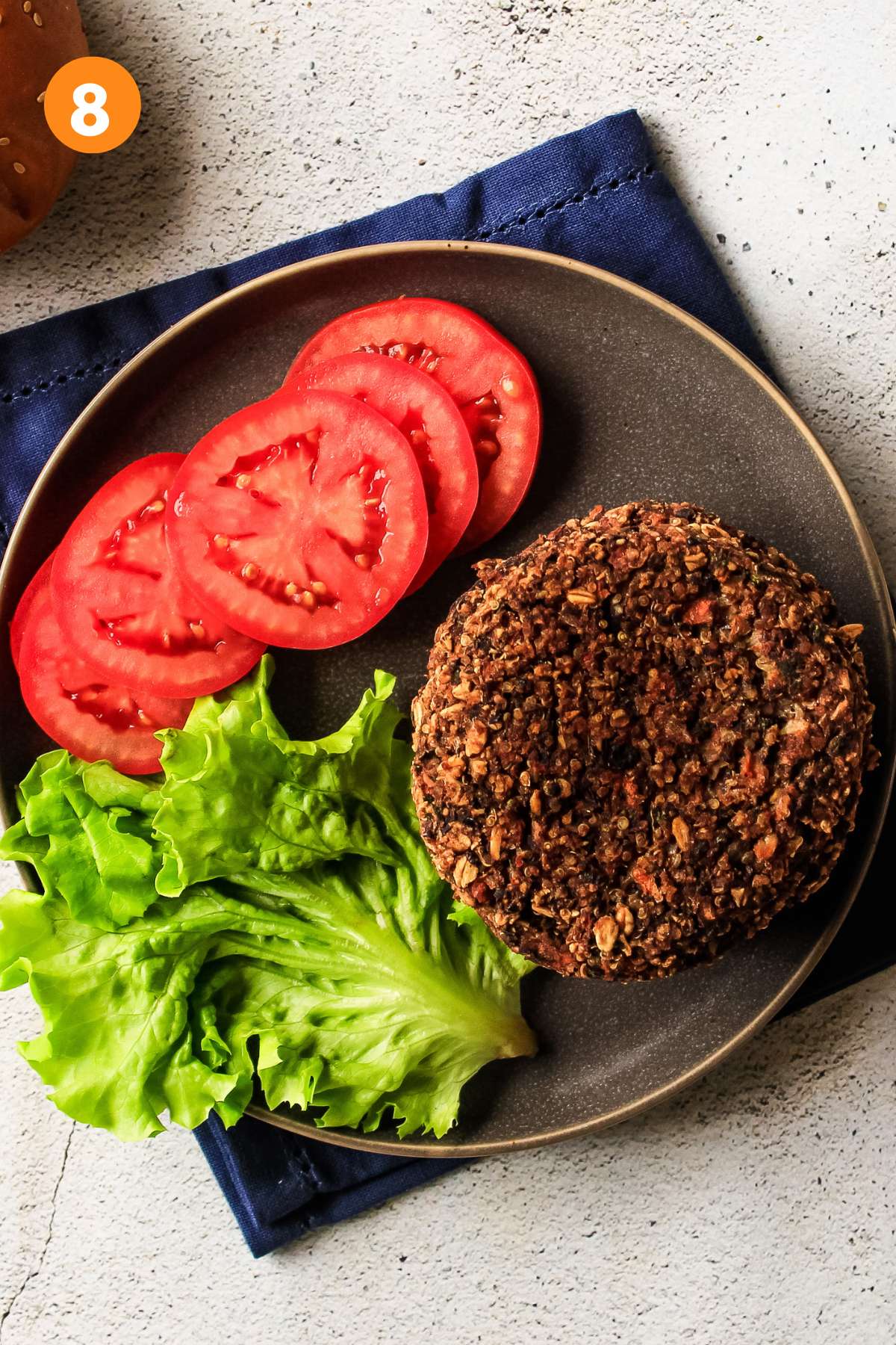 Black bean quinoa burgers on a plate with sliced tomatoes and lettuce.