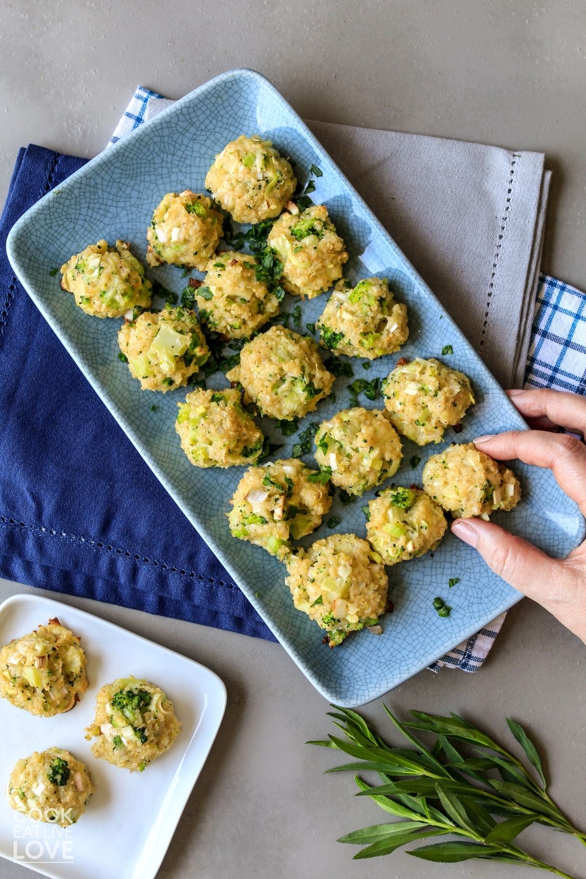 Broccoli quinoa bites on a platter with hand reaching to grab one.
